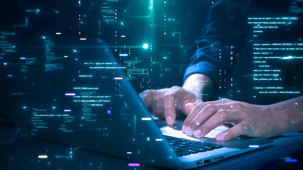 Close-up of hands typing on a laptop with glowing programming code and binary graphics, symbolizing cybersecurity technology coding or software development