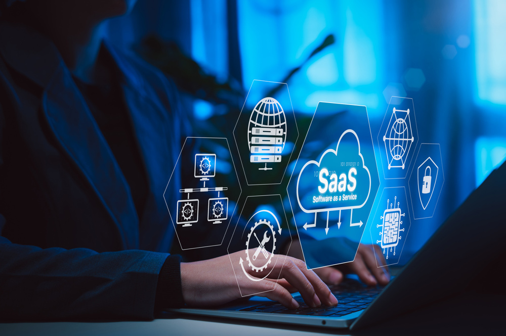 SaaS Software as a Service Cloud Computing Technology. Hands typing on laptop with SaaS icons, cloud systems, data servers, network elements, IT solutions, representing cloud based software solutions