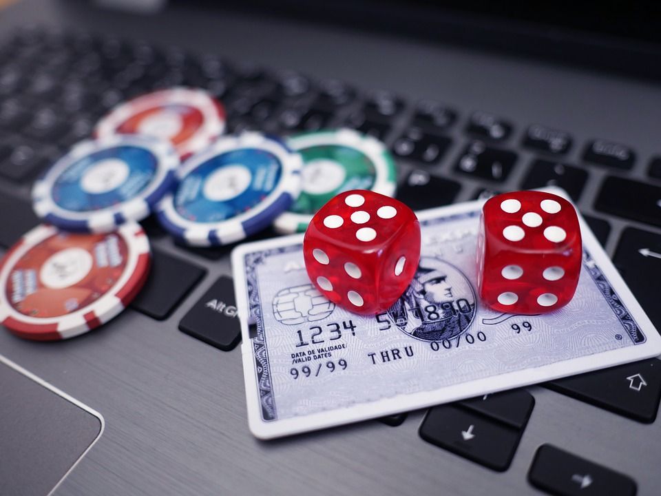 dice, poker chips, and a credit card on a laptop keyboard