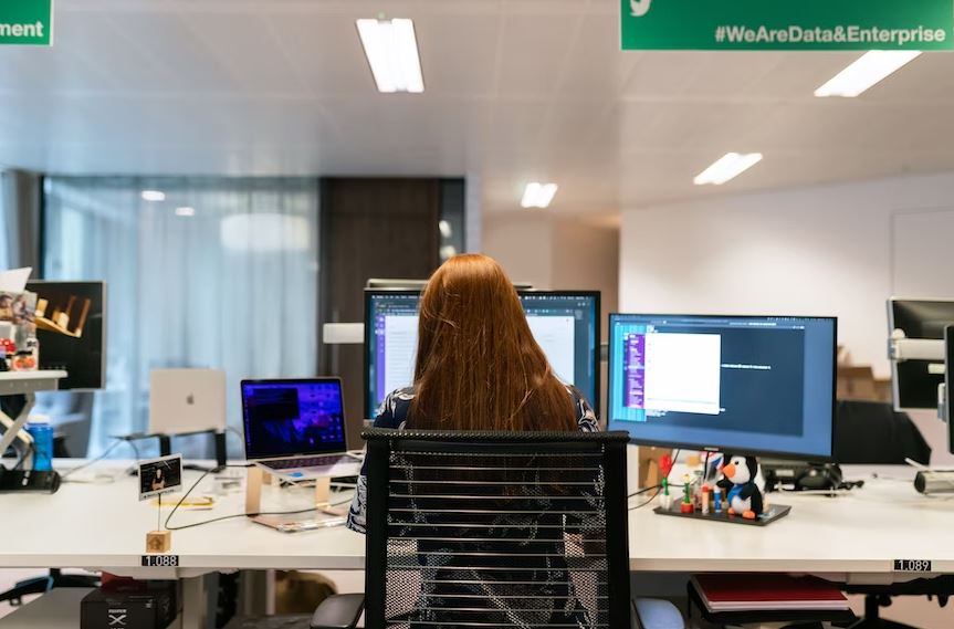Female software engineer works on desk with computers
