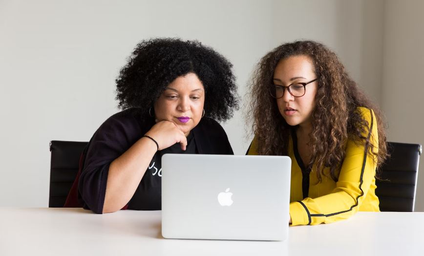 Two curly hair women looking at laptop